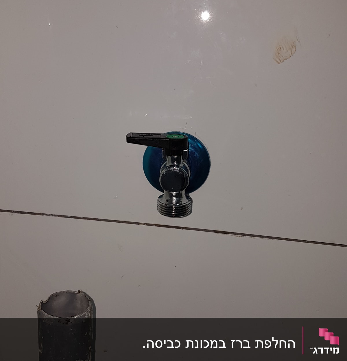 ברז מתכת על קיר לבן עם צינור אפור